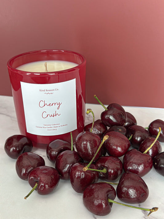 Red candle labeled 'Cherry Crush' with cherries on a white surface