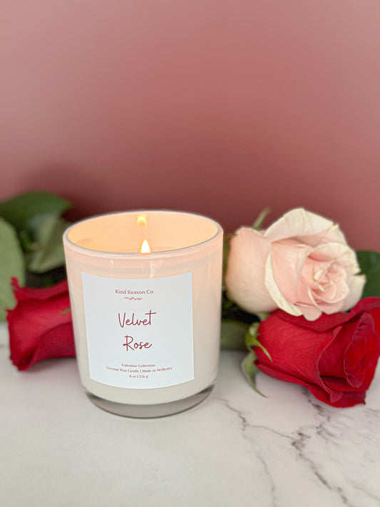Candle labeled 'Velvet Rose' with roses on a marble surface and pink background